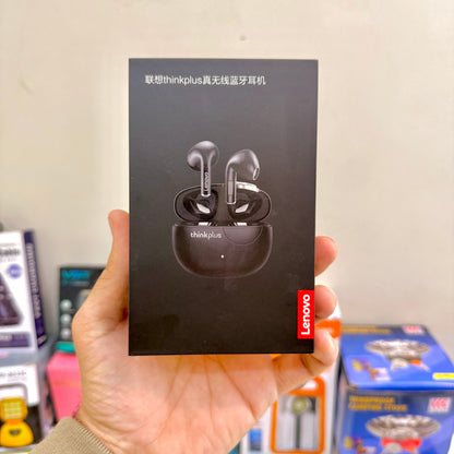 Hand holding a Lenovo Thinkplus wireless Bluetooth earphone box against a blurred indoor background